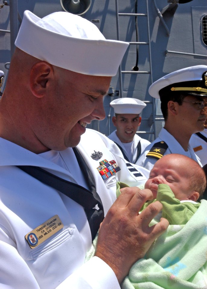 US Navy 050606-N-1356A-038 Torpedoman's Mate 1st Class Keith Kluender holds his newborn son for the first time during the homecoming celebration for guided missile destroyer USS Milius (DDG 69)