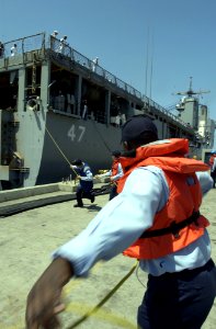 US Navy 050606-N-9866B-041 Line handlers from the amphibious assault ship USS Peleliu (LHA 5) pull in a mooring line as they secure the amphibious dock landing ship USS Rushmore (LSD 47) to the pier