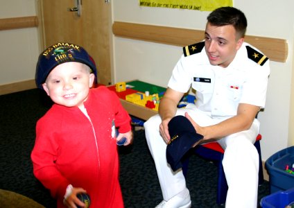 US Navy 050616-N-8110K-048 Boston College graduate, Ens. Luke Tarby presents a ball cap to a young child during Caps for Kids visit