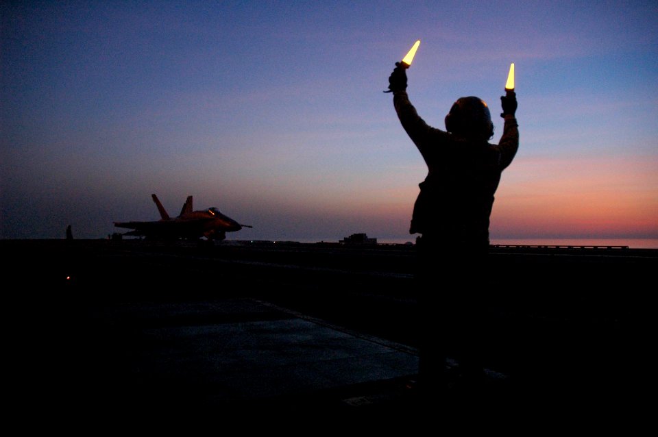 US Navy 050705-N-0000X-010 An aircraft director signals for an F-A-18 Hornet to taxi forward during night flight operations aboard the Nimitz-class aircraft carrier USS Carl Vinson (CVN 70)