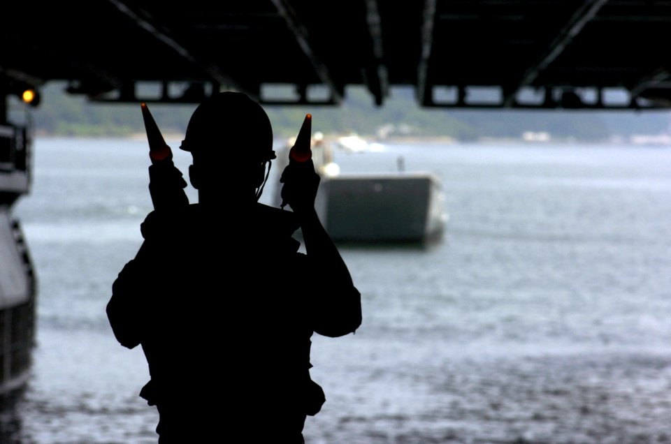 US Navy 050706-N-5067K-037 Seaman Jeremiah Skriba guides Landing Craft, Utility (LCU) 1631, assigned to Assault Craft Unit One (ACU-1), into the well deck aboard the amphibious assault ship USS Essex (LHD 2)