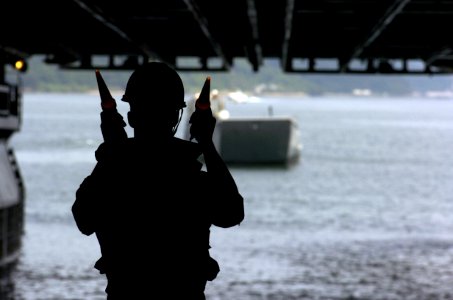 US Navy 050706-N-5067K-037 Seaman Jeremiah Skriba guides Landing Craft, Utility (LCU) 1631, assigned to Assault Craft Unit One (ACU-1), into the well deck aboard the amphibious assault ship USS Essex (LHD 2)