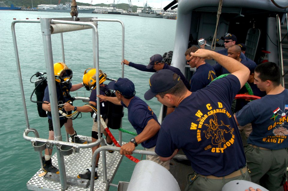 US Navy 050621-N-4104L-033 Dive Supervisor Chief Hull Technician Cliff Morin, foreground, monitors the descent of U.S. Navy diver Engineman 1st Class Joseph Moebius, left, and a Royal Thai Navy diver during a combined indoctrin