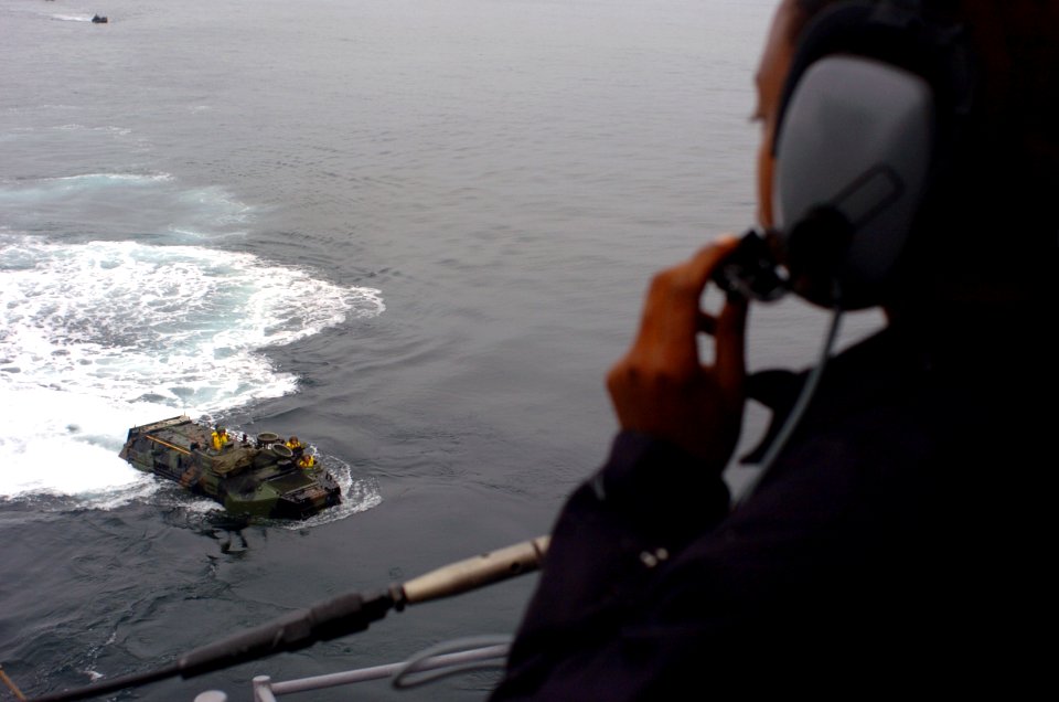 US Navy 050615-N-9866B-008 Seaman Ebony Starr uses a sound-powered telephone to reply the progress of amphibious assault vehicles, assigned to the 3rd Amphibious Assault Battalion, as it prepares to enter the well deck of the a