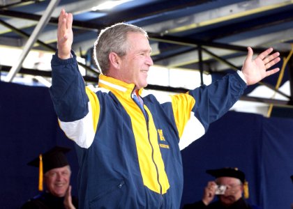 US Navy 050527-N-5390M-206 U.S. President George W. Bush tries on a Naval Academy windbreaker presented to him by a graduating Midshipman during the 2005 Naval Academy Graduation Ceremony