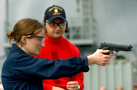 US Navy 050625-N-9866B-032 Chief Gunner's Mate Coby Cosper instructs Ens. Sarah Kolb on the proper firing technique of a 9mm handgun during a live fire weapons qualification photo