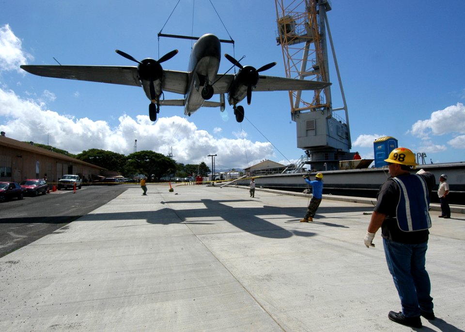 US Navy 050628-N-3019M-001 A line handler directs as a World War II-vintage B-25 Mitchell medium bomber is lowered by crane to the pier after being transported via barge from Hickam Air Force Base to Ford Island
