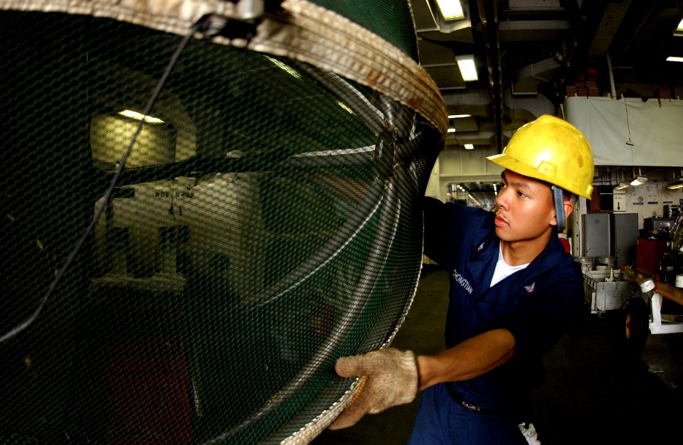 US Navy 050714-N-0413R-021 Aviation Machinist's Mate 3rd Class Jalvin Yuchongtian inspects the cover for an J-52 jet engine