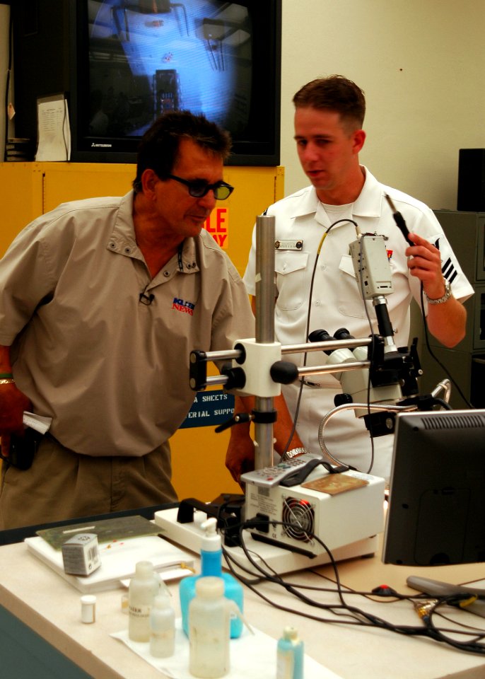 US Navy 050606-N-0050T-038 Electronics Technician 1st Class Dan Shuksta of Phoenix, Ariz., explains procedures on repairing small electronic components