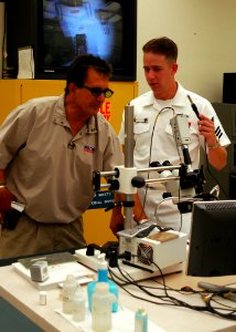 US Navy 050606-N-0050T-038 Electronics Technician 1st Class Dan Shuksta of Phoenix, Ariz., explains procedures on repairing small electronic components