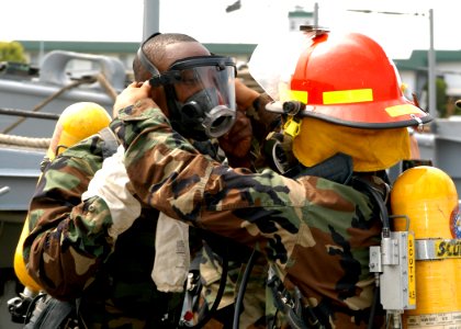 US Navy 050603-N-2385R-069 Electrician's Mate 3rd Class Michael Mosely, left, is assisted by Seaman Brent Honda assigned to Assault Craft Unit One (ACU-1) with donning his Self Contained Breathing Apparatus (SCBA)