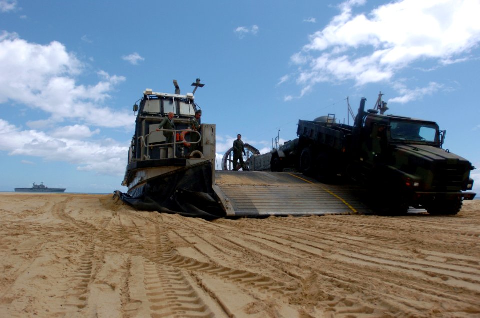 US Navy 050628-N-9866B-006 Sailors assigned to Assault Craft Unit Five (ACU-5) watch as a truck, filled with distilled water, drives off their Landing Craft, Air Cushion (LCAC)