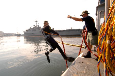 US Navy 050610-N-2385R-061 Aviation Boatswain's Mate 3rd Class Greg Early assists Operations Specialist 3rd Class Shane Olson, a diver assigned to Ships Repair Facility- Japan Regional Maintenance Center, Detachment Saseb