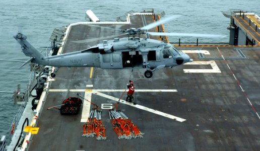 US Navy 050719-N-9866B-001 Two Sailors assigned to the amphibious assault ship USS Peleliu (LHA 5) attach a cargo pendant to a MH-60S Seahawk helicopter