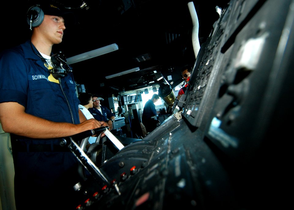 US Navy 050722-N-3019M-008 Seaman Eric Schwarzman mans the helm of the dock landing ship USS Pearl Harbor (LSD 52)