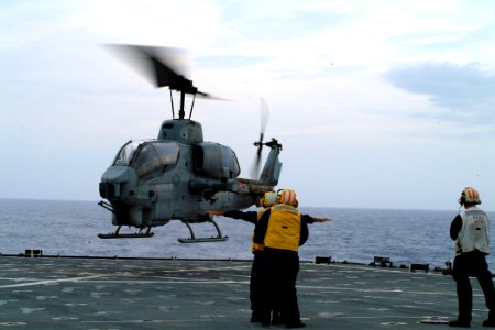 US Navy 050708-N-4772B-027 Lt.j.g. Jeffrey C. Gando is steadied by Storekeeper Seaman Deandre A. Callahan as he directs an incoming U.S. Marine Corps AH-1W Super Cobra