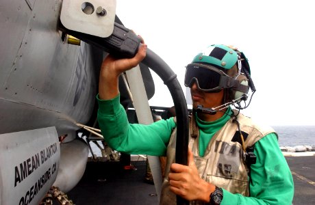 US Navy 050710-N-0413R-009 Aviation Electrician's Mate 1st Class Victor Melendez, assigned to Strike Fighter Squadron Nine Four (VFA-94), plugs an external power cord into an F-A-18E Super Hornet on the flight deck,