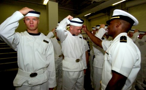 US Navy 050629-N-9693M-252 Midshipman 1st Class Kasisi Harris, right, instructs a Midshipman candidate on the proper wearing of his cover at the United States Naval Academy in Annapolis, Md