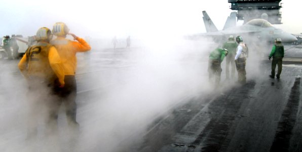 US Navy 050729-N-4308O-021 An Aviation Boatswain's Mate guides an F-A-18F Super Hornet towards the staging prior aboard the Nimitz-class aircraft carrier USS Harry S. Truman (CVN 75)