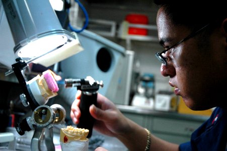 US Navy 050625-N-8158F-026 Dental Technician 3rd Class Ryan Antonio from San Diego, Calif., sculpts a mouth guard for a crewmember aboard the nuclear-powered aircraft carrier USS Nimitz (CVN 68)