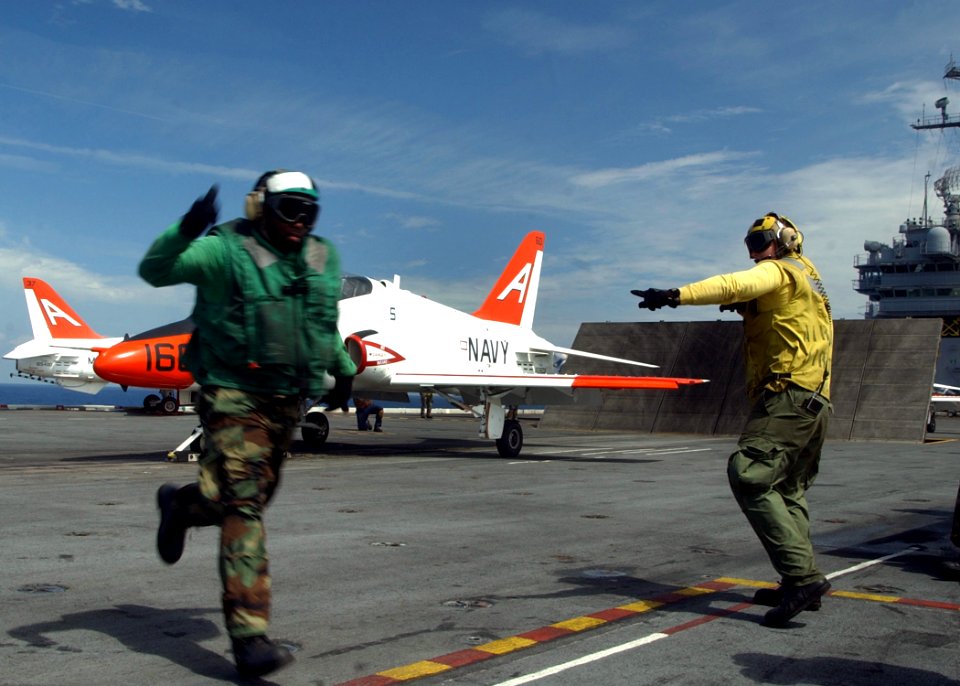 US Navy 050731-N-8704K-002 An Aviation Boatswain Mate signals that a T-45 Goshawk is clear to launch from the flight deck of the conventionally powered aircraft carrier USS John F. Kennedy (CV 67)