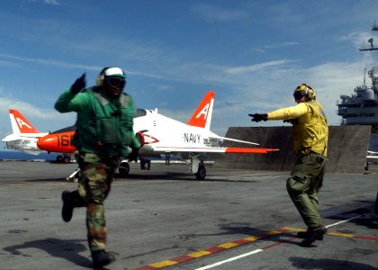 US Navy 050731-N-8704K-002 An Aviation Boatswain Mate signals that a T-45 Goshawk is clear to launch from the flight deck of the conventionally powered aircraft carrier USS John F. Kennedy (CV 67)