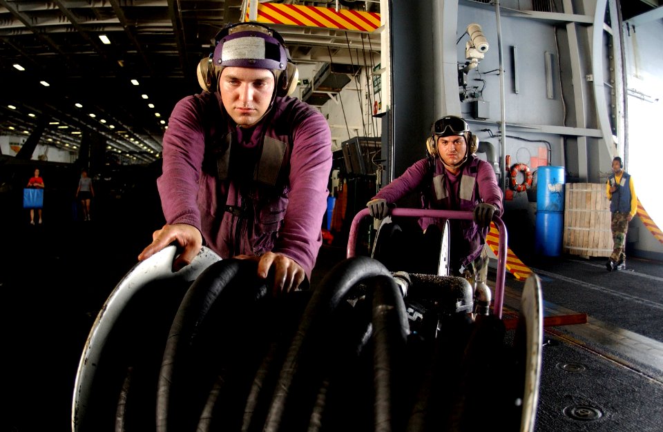US Navy 050715-N-0413R-015 Airman Richard Vananne and Aviation Boatswain's Mate 3rd Class Max Melgar prepare to swap-out a de-fuel cart in the hangar bay aboard the nuclear-powered aircraft carrier USS Nimitz (CVN 68)