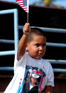 US Navy 050729-N-3019M-005 The son of a Sailor assigned aboard the guided missile destroyer USS O'Kane (DDG 77) waves an American flag as the ship returns to Pearl Harbor from a six-month deployment