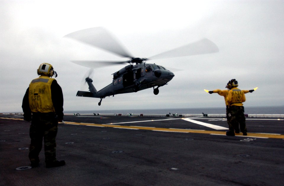 US Navy 050804-N-9866B-053 Aviation Boatswain's Mates direct a MH-60S Seahawk to land on the flight deck of the amphibious assault ship USS Peleliu (LHA 5)