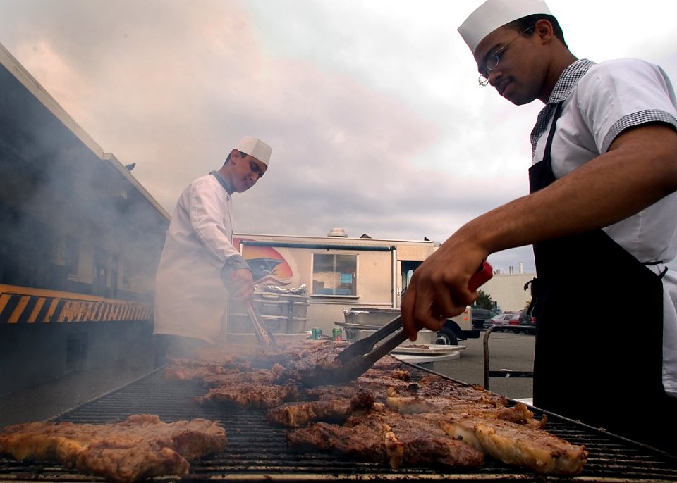 US Navy 050823-N-5134J-039 Culinary Specialist Seaman Shaun Lucas and Culinary Specialist Seaman Jaime Pablo prepare for lunch at the galley by grilling T-bone steaks