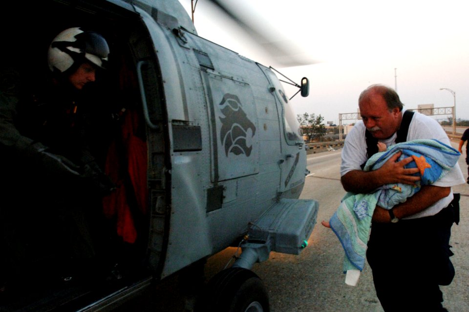 US Navy 050831-O-0000A-001 A member of the Federal Emergency Management Agency (FEMA) Urban Search and Rescue Task Force rushes a baby to a U.S. Navy air crewman prior to being medically evacuated from New Orleans