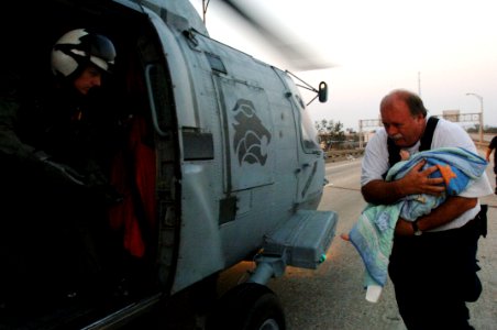 US Navy 050831-O-0000A-001 A member of the Federal Emergency Management Agency (FEMA) Urban Search and Rescue Task Force rushes a baby to a U.S. Navy air crewman prior to being medically evacuated from New Orleans
