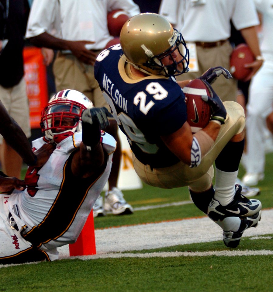 US Navy 050903-N-9693M-001 U.S. Naval Academy Midshipman 1st Class Marco Nelson falls over the goal line in the first quarter as Maryland Terepin defender Josh Wilson tries to block