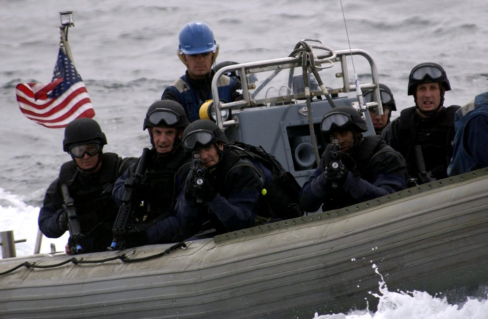 US Navy 050816-F-9085B-009 U.S. Coast Guard's Marine Safety and Security Team (MSST) stand ready with weapons drawn as they are transported in one of USS Ogden's (LPD 5) Rigid Hull Inflatable Boats
