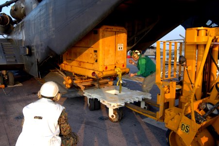 US Navy 050903-N-8154G-203 Crew members assigned to the amphibious assault ship USS Bataan (LHD 5) work with combat cargo and Helicopter Mine Countermeasure Squadron Fifteen (HM-15) personnel to pull a generator from the interi