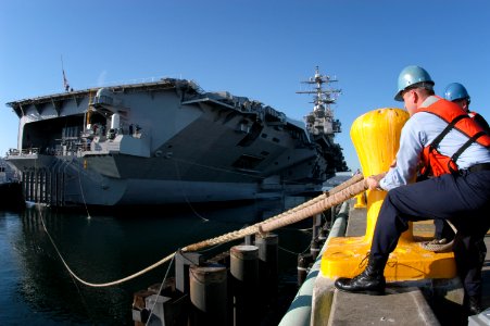 US Navy 050908-N-6477M-271 Hull Technician 1st Class Chance D. Barker casts off a line from the pier as the Nimitz-class aircraft carrier USS Abraham Lincoln (CVN 72) prepares for departure from Naval Station Everett, Wash photo