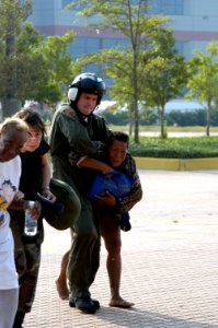 US Navy 050903-N-1467R-025 U.S. Navy Aviation Machinist's Mate 2nd Class Kirk Crabb helps a Hurricane Katrina survivor walk to a U.S. Navy MH-53E Sea Dragon helicopter