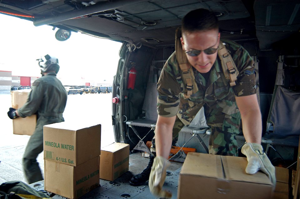 US Navy 050902-N-8154G-004 U.S. Navy personnel and U.S. Air Force reservists work together to unload cases of water from a Navy SH-60 Seahawk helicopter at an airfield near Biloxi, Miss