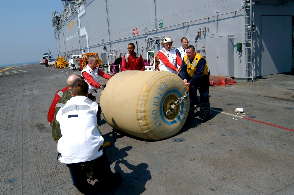 US Navy 050903-N-8154G-030 Crew members aboard the amphibious assault ship USS Bataan (LHD 5) work together to move a rubber bladder holding 500 gallons of fresh drinking water for transport