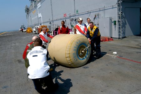 US Navy 050903-N-8154G-030 Crew members aboard the amphibious assault ship USS Bataan (LHD 5) work together to move a rubber bladder holding 500 gallons of fresh drinking water for transport