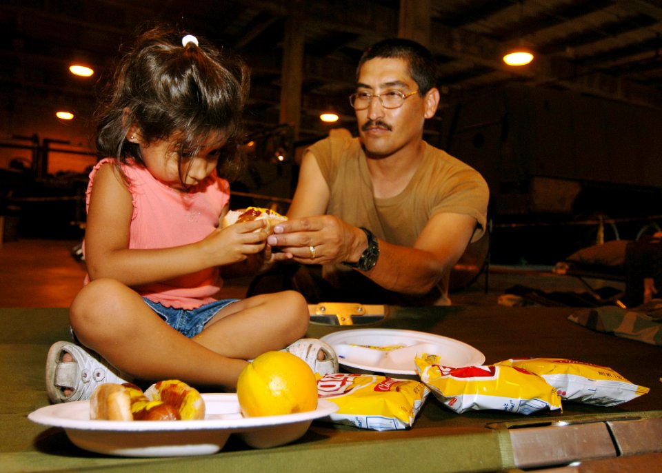 US Navy 050903-N-4374S-001 U.S. Navy Seabee, Construction Mechanic 1st Class Jesus Reyna, assigned to Naval Mobile Construction Battalion Seven (NMCB-7), takes time to eat lunch with his daughter