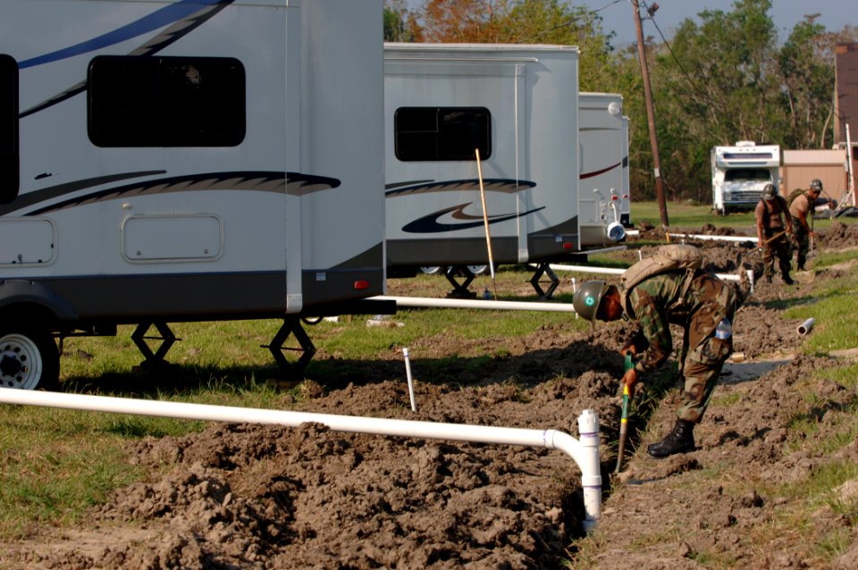 US Navy 050928-N-2653P-009 Seabees from Naval Mobile Construction Battalion Four Zero (NMCB-40) install sewage pipes for an evacuee relocation trailer site