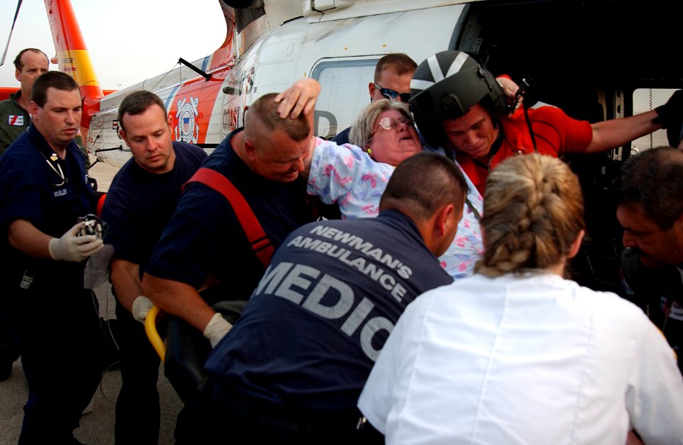 US Navy 050901-C-3721C-251 A U.S. Coast Guard helicopter rescue crew and paramedics from the Mobile, Ala., area assist a Hurricane Katrina survivor onto a gurney at the Mobile Coast Guard base