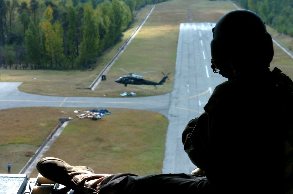US Navy 051012-N-8796S-241 A U.S. Army aircrew member sits in the ramp of a CH-47 Chinook helicopter as a UH-60 Blackhawk helicopter takes off below after dropping off emergency aid to the remote Pakistani village of Rawalakot