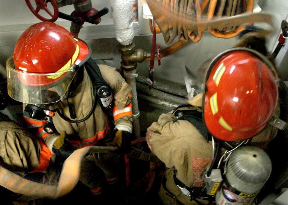 US Navy 050923-N-0716S-004 Damage Control Fireman Eric Kirby and Machinery Repairman 3rd Class Charles Bozora unwind a fire hose to be used during a fire drill aboard the amphibious assault ship USS Tarawa (LHA 1)