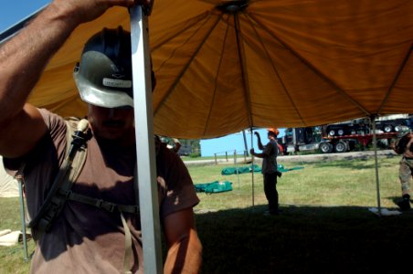 US Navy 050928-N-2653P-027 Construction Electrician 3rd Class German Liracarillo assigned to Naval Mobile Construction Battalion Four Zero (NMCB-40) helps assemble a tent, which is part of a larger 500 person Federal Emergency