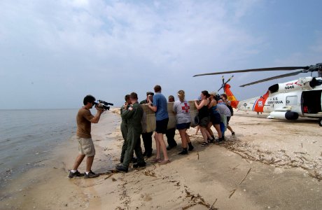 US Navy 050928-C-9767K-330 U.S. Coast Guard crewmen, Texas Marine Mammal Stranding Network members and a Master Sergeant with the Louisiana Army National Guard carry a 7-foot, 400-pound dolphin to the Gulf of Mexico photo