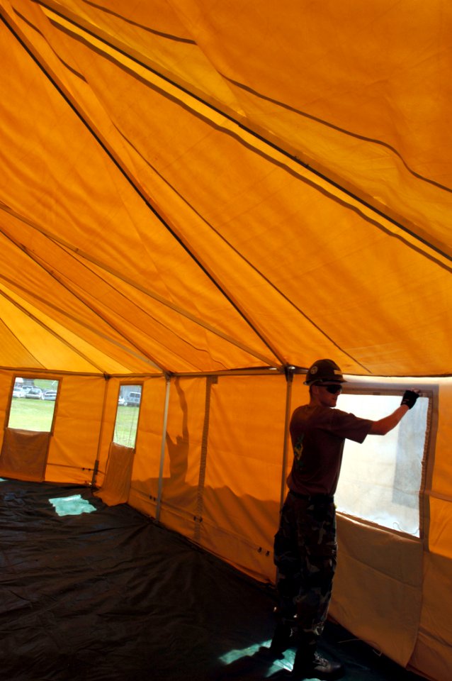 US Navy 050928-N-2653P-035 Construction Electrician Tom Lucy assigned Naval Mobile Construction Battalion Four Zero (NMCB-40) helps assemble a tent, which is part of a larger 500 person Federal Emergency management Agency (FEMA