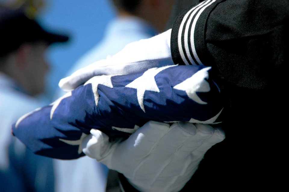 US Navy 051013-N-6106R-117 A member of the flag detail prepares to present a folded American flag to Chief Aviation Boatswain's Mate Michael Berry at his retirement ceremony