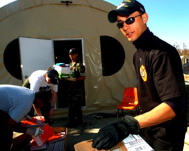 US Navy 051025-N-3729H-045 U.S. Navy Airman Jagen Joy, assigned to the Nimitz-class aircraft carrier USS John C. Stennis (CVN 74), helps locals move boxes of supplies out of storage tents